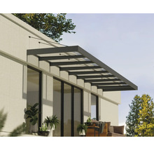 Moderní terasová střecha z hliníku a skla na světlé stěně domu nad zařízenou terasou.