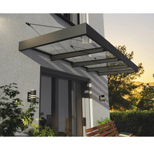 Moderní stříška ze skla a kovu nad terasovými dveřmi na stěně domu s nástěnnými svítidly a dřevěnou lavičkou.