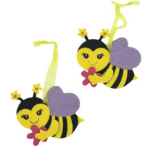 Dva dekorativní včelí přívěsky s květinami v rukou a poutky k zavěšení.