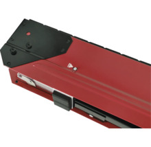 Detailní pohled na červený držák okenního parapetu s černým krytem a upevňovacími prvky