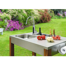 Venkovní kuchyně s dřezem, baterií, zeleninou, šampaňským a držákem papírových ručníků na zahradě