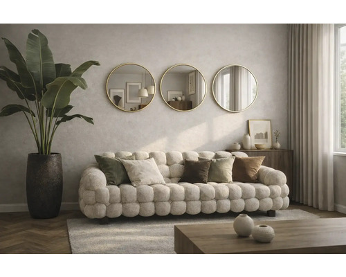 Obývací pokoj s čalouněnou pohovkou, dekorativními polštáři, pokojovou rostlinou v květináči a třemi kulatými zrcadly na zdi.