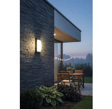 Osvětlená terasa s nástěnným svítidlem, dřevěným stolem a světelným řetězem na zahradě