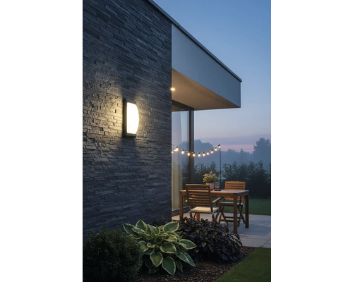 Osvětlená terasa s nástěnným svítidlem, dřevěným stolem a světelným řetězem na zahradě