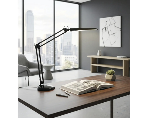 Stůl s lampou s otočným ramenem, knihou a pery ve světlé kanceláři.