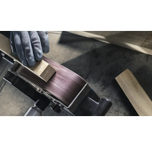 Detail pásové brusky zpracovávající obrobek