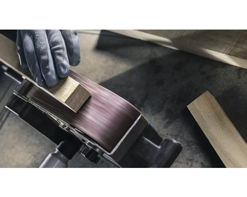 Detail pásové brusky zpracovávající obrobek