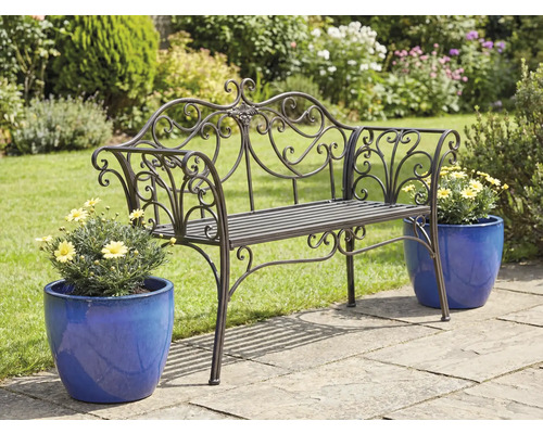 Zdobená kovová zahradní lavička s květináči na zahradní terase