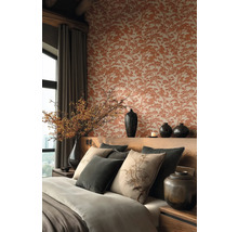 Elegantní ložnice s tapetou se vzorem stromů, dřevěným čelem postele, dekorativními polštáři s botanickými motivy a tmavými keramickými vázami.