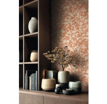 Vliesová tapeta se vzorem borovic v rezavém vzhledu za tmavou dřevěnou policí s keramickými vázami a knihami.