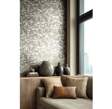 Vliesová tapeta se vzorem borovic v obývacím pokoji s pohovkou, dekorativními polštáři a keramickými vázami na komodě u okna.