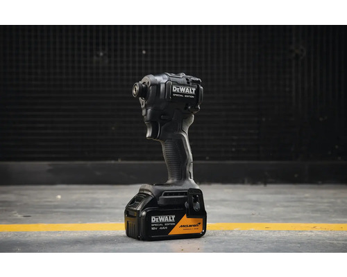 Akumulátorový rázový utahovák DeWALT Special Edition McLaren s 18 Volt 4 ampérhodinovou baterií stojící na šedé podlaze.