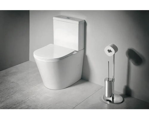 Stojící WC kombi z keramiky s nádržkou a sedátkem vedle chromovaného stojanu na toaletní papír a WC kartáče v koupelně.