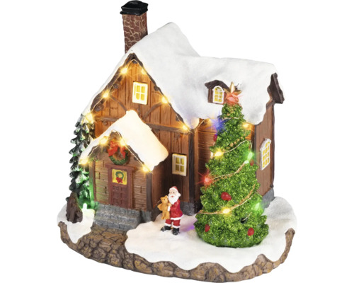 Vánoční vesnička miniatura se zasněženým domkem, osvětleným stromkem, figurkou Santa Clause a světelným řetězem.