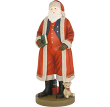 Figurka Santa Clause v červeném kabátě s kožešinou, drží zelenou knihu, vedle něj medvídek a dárky na kulatém podstavci.
