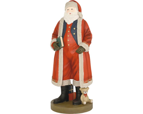Figurka Santa Clause v červeném kabátě s kožešinou, drží zelenou knihu, vedle něj medvídek a dárky na kulatém podstavci.