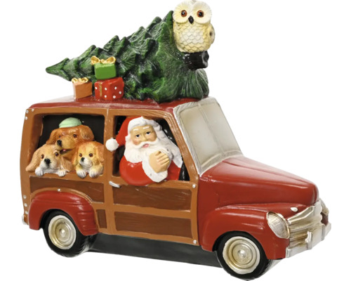 Vánoční figurka Santa Klaus za volantem červeného auta se třemi psy, vánočním stromkem, dárky a sovou na střeše.