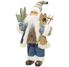 Dekorativní figurka Santa Clause s lyžemi, brýlemi a jedlovou větví, v pleteném svetru, modrém kabátě a kalhotách s bílým kožešinovým lemem.