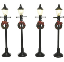 Sada čtyř černých miniaturních pouličních lamp s vánočním věncem a červenou mašlí.