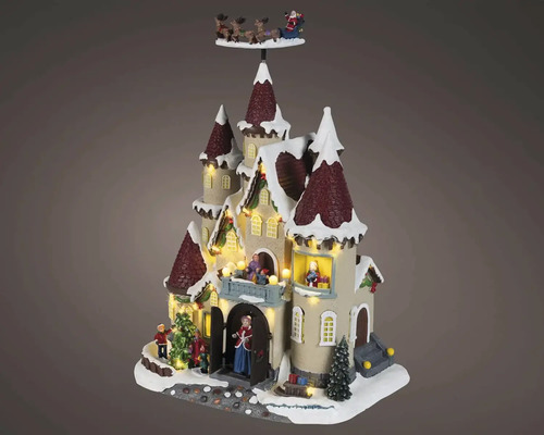 Osvětlený vánoční hrad s figurkami, vánočními stromky a létajícími sáněmi nad zasněženými věžemi, LED osvětlení.