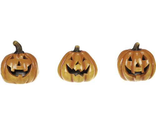 Tři dekorativní halloweenské dýně s vyřezanými obličeji.
