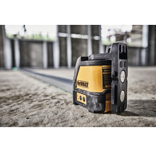 Křížový laser DeWalt na betonové podlaze v novostavbě pro přesné vyrovnání.