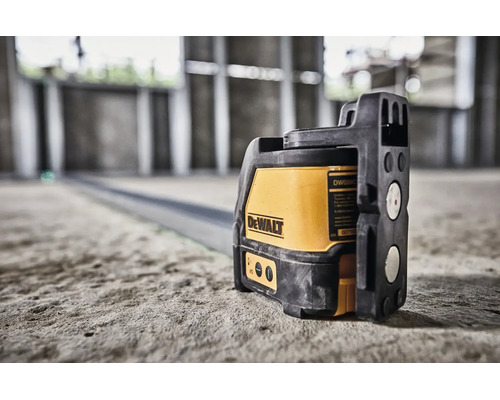 Křížový laser DeWalt na betonové podlaze v novostavbě pro přesné vyrovnání.