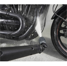 Tryska vysokotlakého čističe čistí motor motocyklu proudem vody.