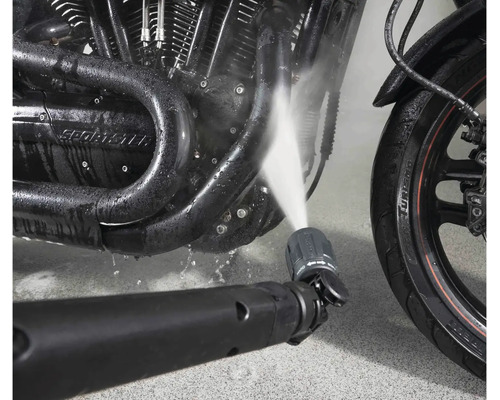 Tryska vysokotlakého čističe čistí motor motocyklu proudem vody.