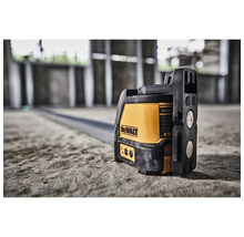 Křížový laser DeWalt na betonové podlaze v rozestavěné budově pro přesné vyrovnání.