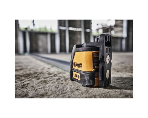 Křížový laser DeWalt na betonové podlaze v rozestavěné budově pro přesné vyrovnání.
