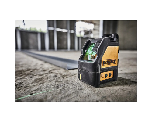 Křížový laser DeWalt na betonové podlaze na staveništi promítá zelenou laserovou linku na kovový profil