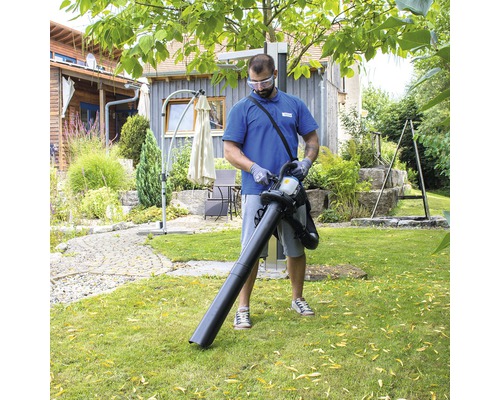 Muž používá vysavač listí na zahradě.