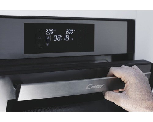 Detailní záběr trouby Candy s rukou na rukojeti a digitálním displejem
