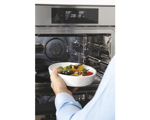 Osoba vkládá mísu se zeleninou do trouby