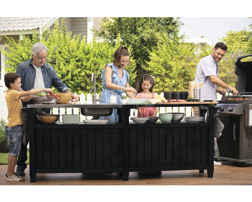 Rodina připravuje jídlo na grilovacím ostrůvku v zahradě