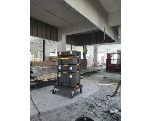 Černá věž ze skříněk na nářadí na pojízdné desce ve světlém prostředí staveniště