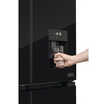 Černá chladnička s dávkovačem vody a osobou plnící sklenici vody.