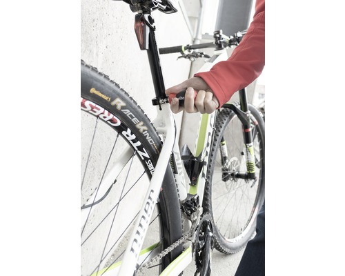 Detailní záběr na kolo, jehož sedlovka je nastavována nástrojem.