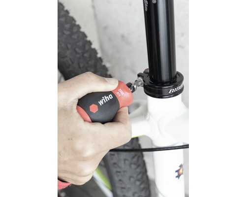 Osoba upevňuje sedlovku jízdního kola šroubovákem Wiha.