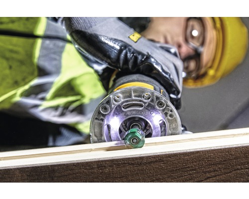 Detailní záběr horní frézky, kterou obsluhuje osoba s ochrannou přilbou a rukavicemi