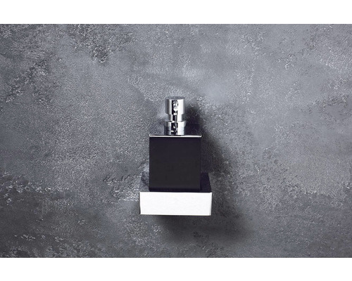 Černý flakon parfému se stříbrným rozprašovačem na bílém obalu