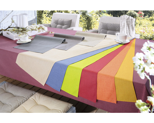Prostřený stůl s ubrusy různých barev pro venkovní použití.