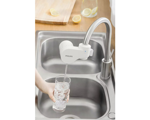 Vodovodní kohoutek s nástavcem vodního filtru Philips plnící sklenici vody v umyvadle