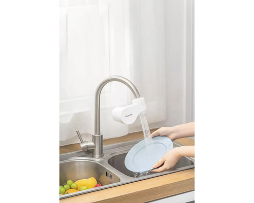 Kuchyňská scéna s umyvadlem, kohoutkem s filtrem a rukama myjící talíř.