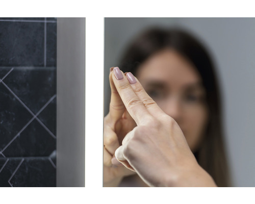 Žena se dotýká osvětleného koupelnového zrcadla