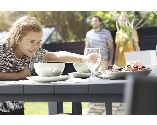 Venkovní scéna s jídelním stolem, nádobím, nápoji a rodinou