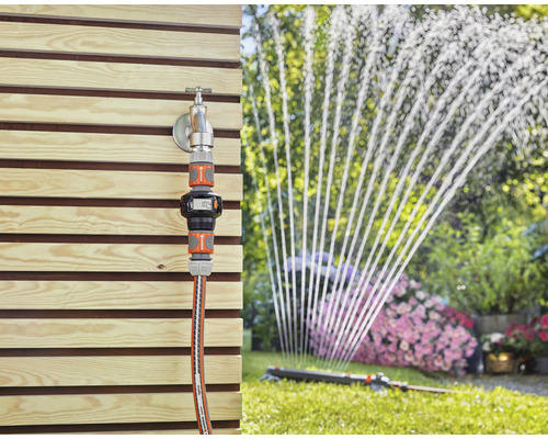 Zahradní scéna s vodovodním kohoutkem, vodoměrem Gardena a zavlažovačem trávníku