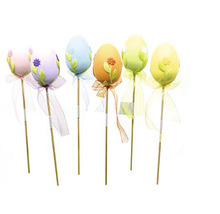 Dekorativní velikonoční vajíčka na tyčkách s květinovými motivy a stuhami.