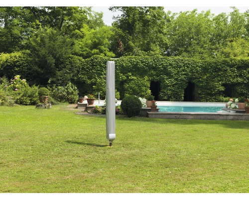 Uzavřený zahradní slunečník s ochranným obalem na trávníku v zahradě s bazénem